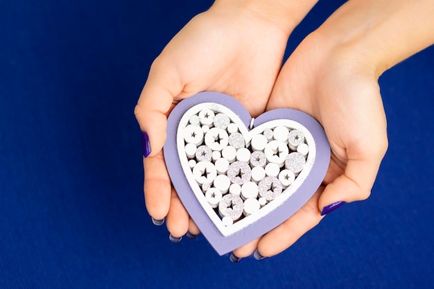 Foto las manos femeninas del día de san valentín sosteniendo un corazón blanco sobre un fondo azul