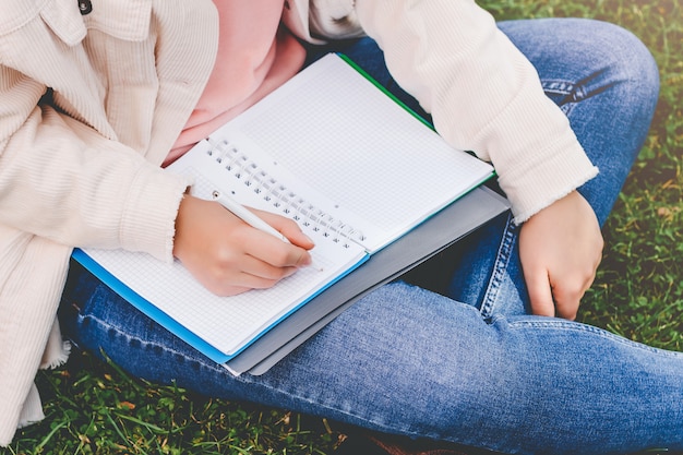 Las manos femeninas escriben en un cuaderno.