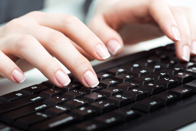 Manos femeninas escribiendo en la computadora portátil, cerrar