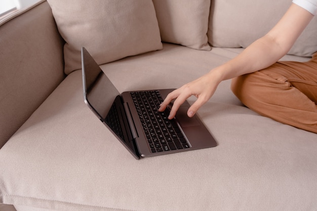 Manos femeninas escribiendo en una computadora portátil.