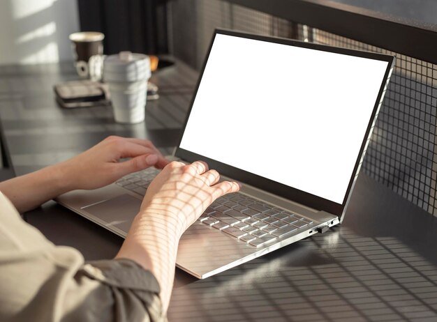 Manos femeninas escribiendo en el teclado de una computadora portátil mujer sentada en un café y usando una maqueta de computadora en el trabajo o en St.