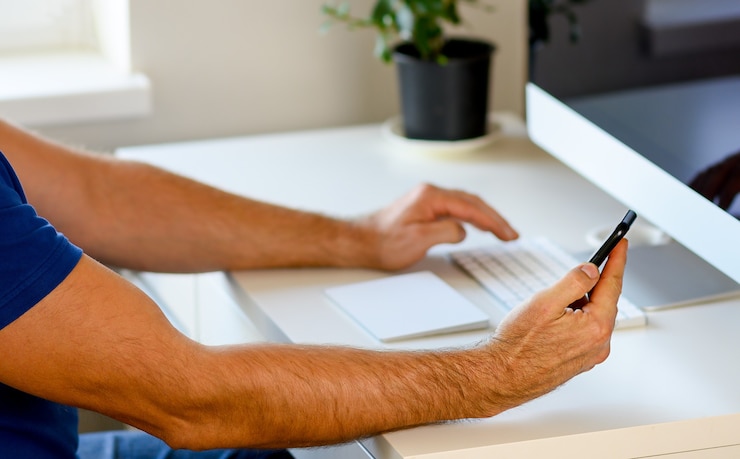 Foto manos femeninas escribiendo en el teclado del portátil en la oficina, en casa, teléfono en mano
