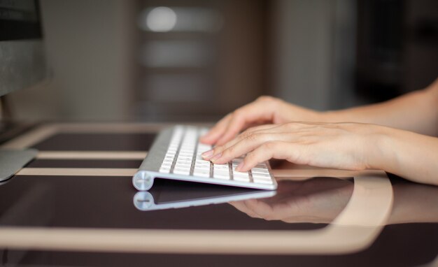 Manos femeninas escribiendo texto en el teclado mientras intercambia mensajes con amigos