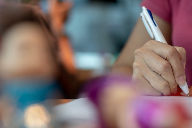 Manos femeninas con la escritura de la pluma en el cuaderno