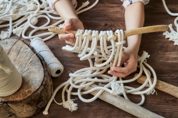 Foto manos femeninas en un espacio de trabajo que muestra cómo hacer una decoración de macramé