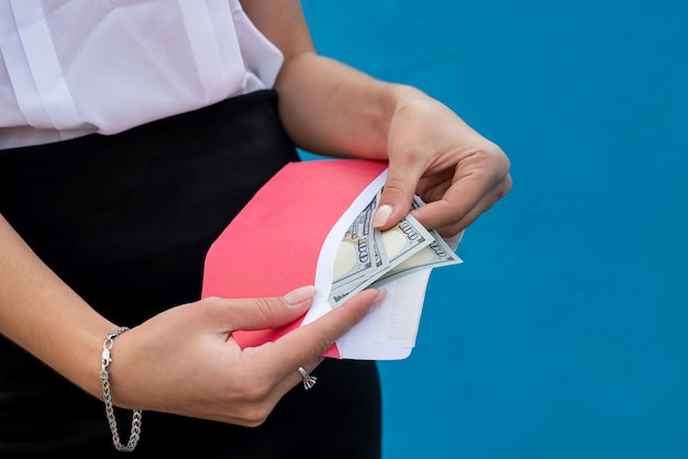 Foto manos femeninas esposadas sosteniendo un sobre con dólares. el concepto de corrupción y soborno