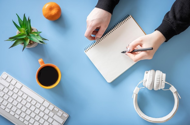 Manos femeninas están escribiendo en un minimalismo conceptual laico plano de cuaderno