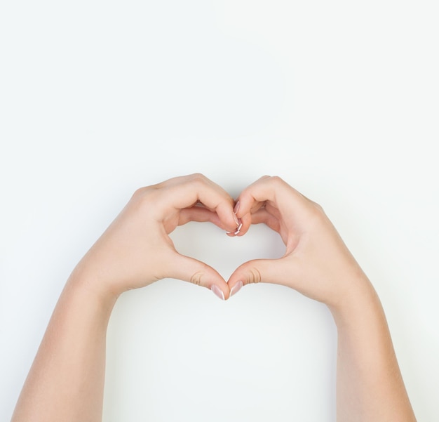 Manos femeninas con forma de corazón sobre fondo blanco Concepto de manicura