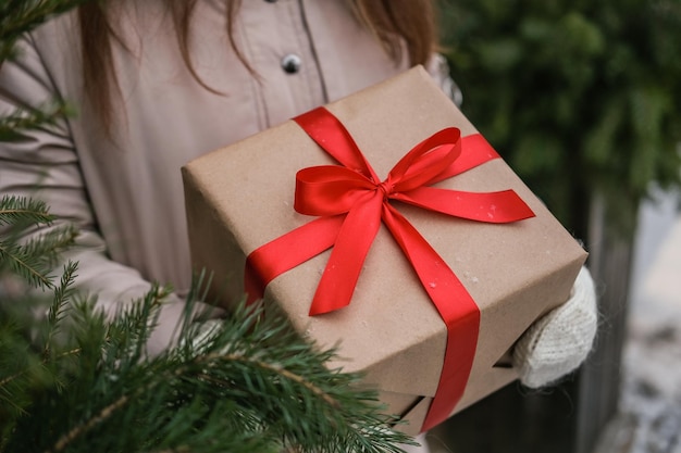 Manos femeninas en guantes de lana con caja de regalo de navidad