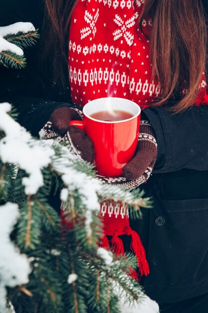 Manos femeninas en guantes sosteniendo una taza de té