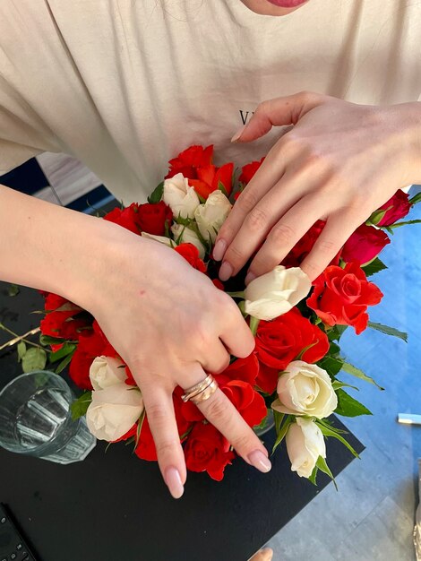 Las manos femeninas hacen un hermoso ramo de pequeñas rosas rojas y blancas.