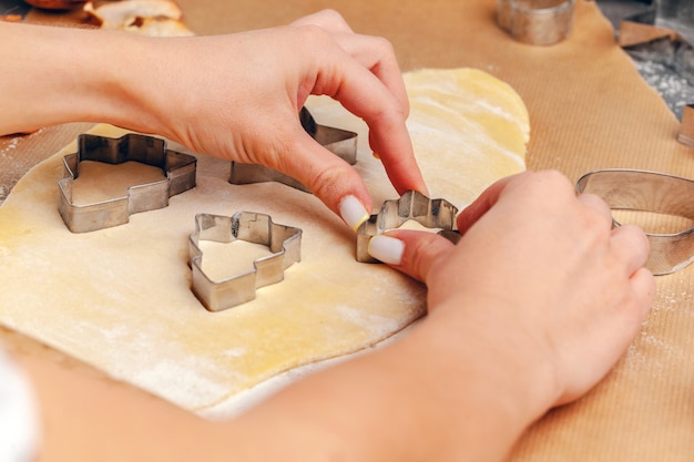 manos femeninas haciendo galletas de masa fresca en casa