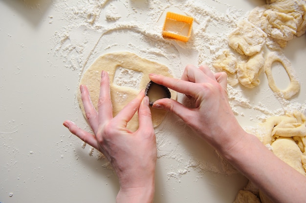 Manos femeninas haciendo galletas de masa fresca