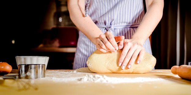 Manos femeninas haciendo masa en mesa de madera