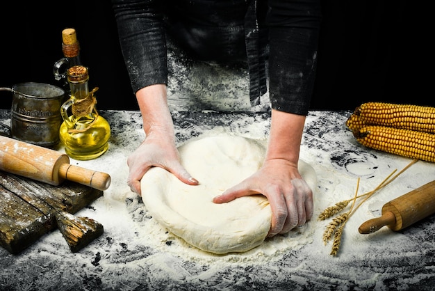 Manos femeninas haciendo masa para pan con salpicaduras de harina Fondo de cocina