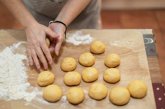 Foto manos femeninas haciendo pequeñas bolas con pastel corto crudo