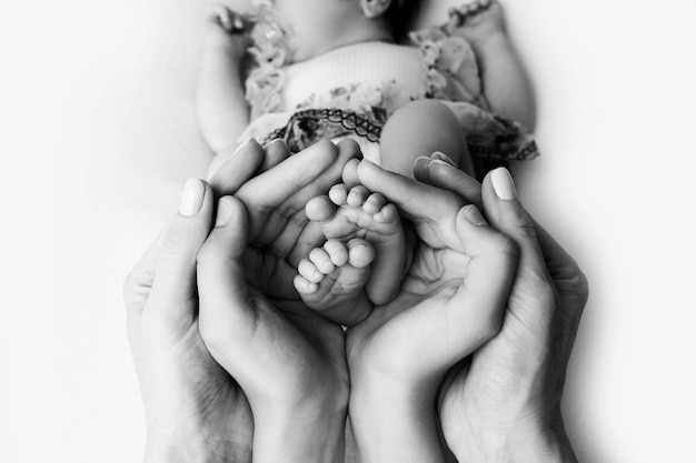 Manos femeninas de la joven madre sosteniendo sus pies de bebé, imagen de primer plano con desenfoque de fondo de bebé. Foto de alta calidad