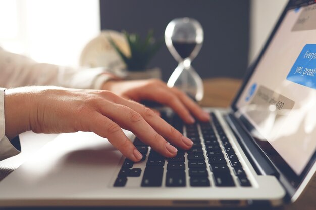 Manos femeninas jóvenes con hermosa manicura escribiendo texto en la computadora portátil en el escritorio. Trabajar con una computadora portátil en casa o en la oficina. De cerca.