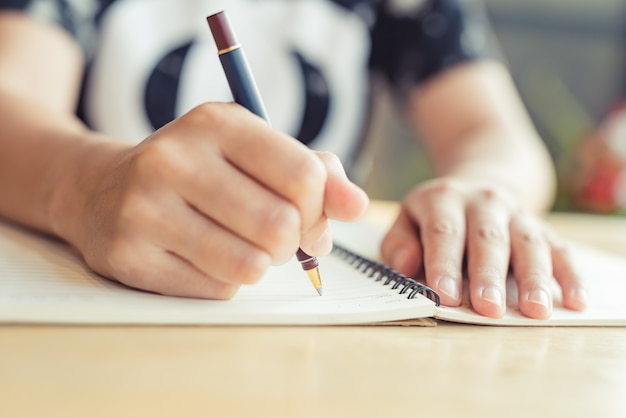 Manos femeninas con lápiz escribiendo en el cuaderno - Imagen