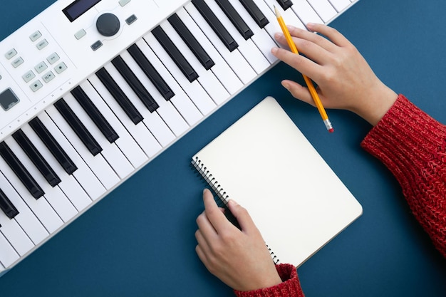 Manos femeninas libreta vacía y teclas de música sobre fondo verde vista superior concepto de creatividad musical