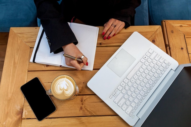 Manos femeninas con manicura roja en el fondo de una laptop blanca