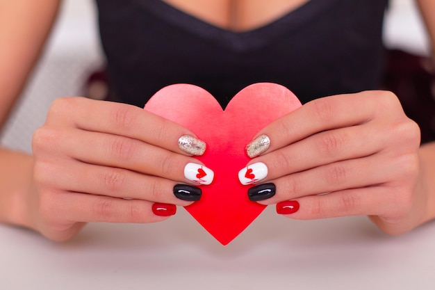 Foto manos femeninas con uñas de manicura románticas, diseño de corazones