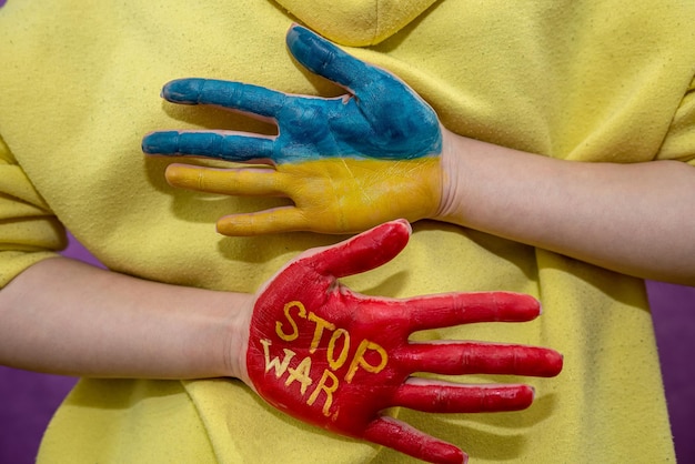 Manos femeninas una mano en el color nacional de ucrania azul amarillo y la otra mano roja detener la guerra Conflicto militar con Rusia