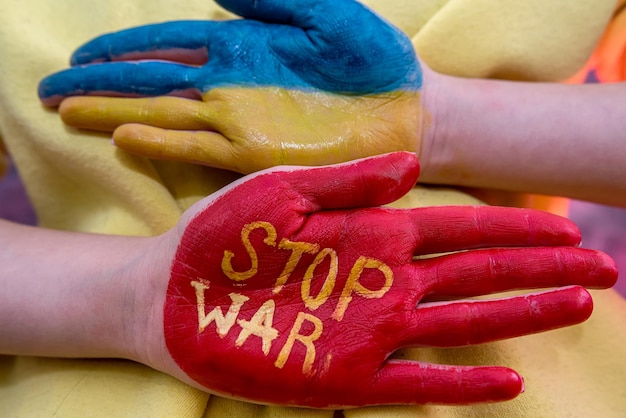 Manos femeninas una mano en el color nacional de ucrania azul amarillo y la otra mano roja detener la guerra Conflicto militar con Rusia