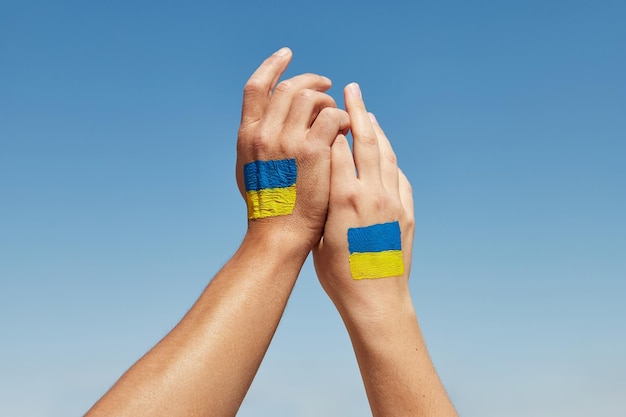 Manos femeninas y masculinas pintadas con los colores de la bandera de ucrania sosteniendo detener la guerra