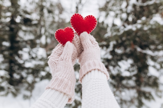 Manos femeninas en mitones con corazón decorativo rojo para el día de San Valentín.