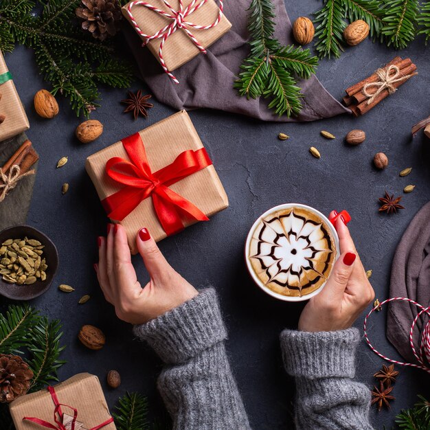 Manos femeninas de Navidad con cajas de regalo y taza de café