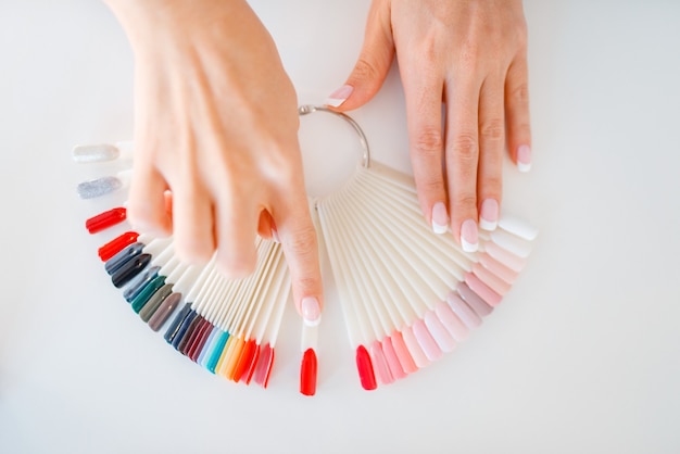 Manos femeninas y paleta de colores de esmalte de uñas