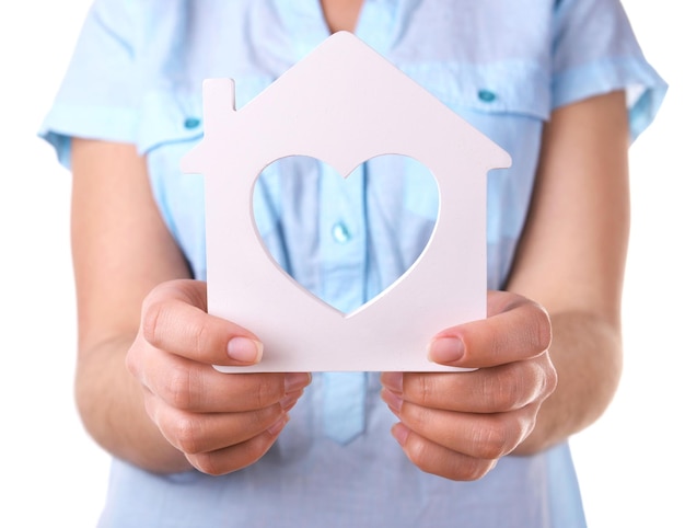 Manos femeninas con pequeño modelo de casa aislada en blanco