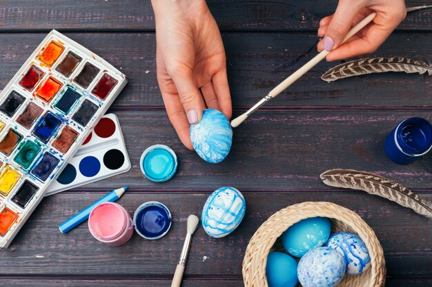 Manos femeninas pintando huevos de Pascua