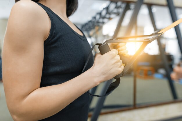 Manos femeninas de primer plano con correas de fitness en el gimnasio