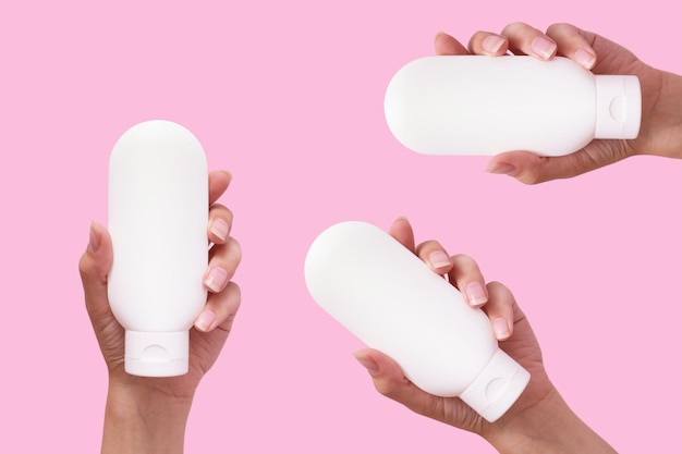 Manos femeninas con productos cosméticos en recipientes blancos se burlan de fondo de color rosa