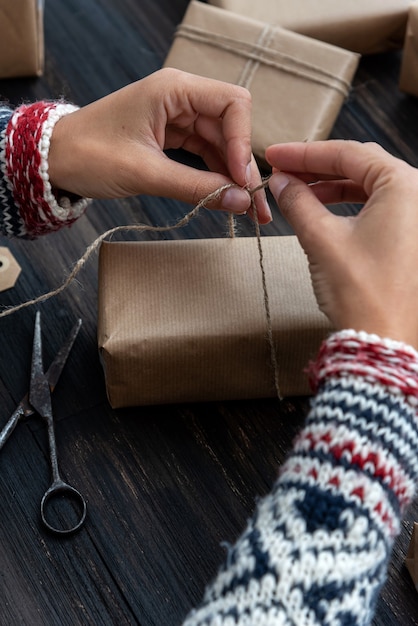 Foto manos femeninas que envuelven la caja de regalo de navidad