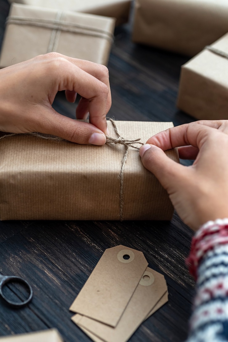 Foto manos femeninas que envuelven la caja de regalo de navidad