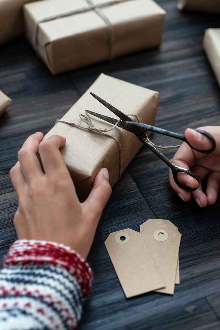 Foto manos femeninas que envuelven la caja de regalo de navidad