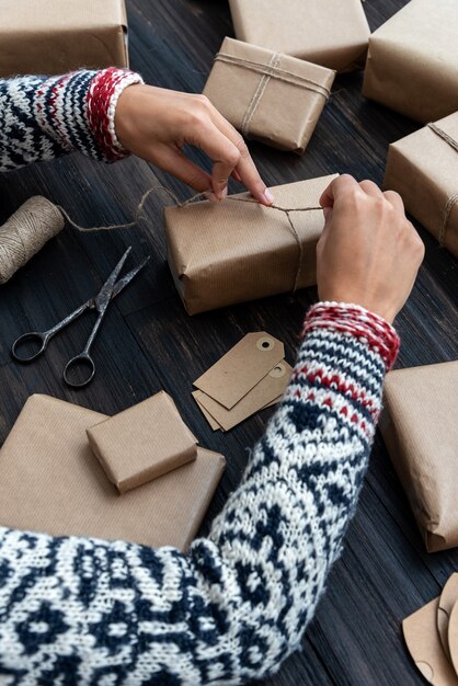 Foto manos femeninas que envuelven la caja de regalo de navidad