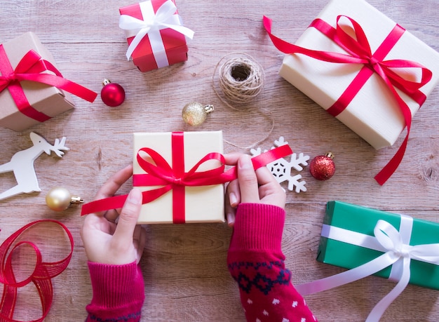 Manos femeninas que envuelven la caja de regalo.