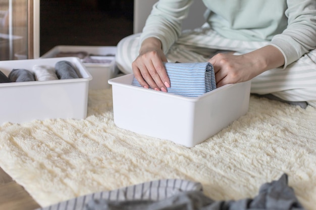 Manos femeninas que organizan el almacenamiento de ropa interior calcetines camisetas utilizan el método marie kondos perfeccionista