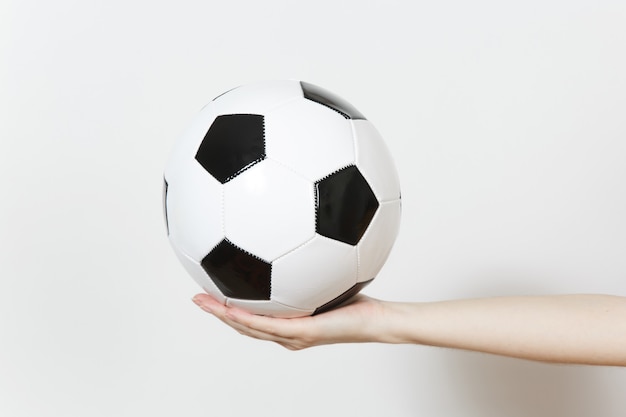 Manos femeninas que sostienen la bola negra blanca clásica del fútbol aislada en el fondo blanco. Deporte, fútbol, salud, concepto de estilo de vida saludable.