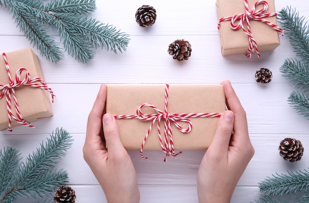 Manos femeninas que sostienen la caja de regalo en un fondo blanco