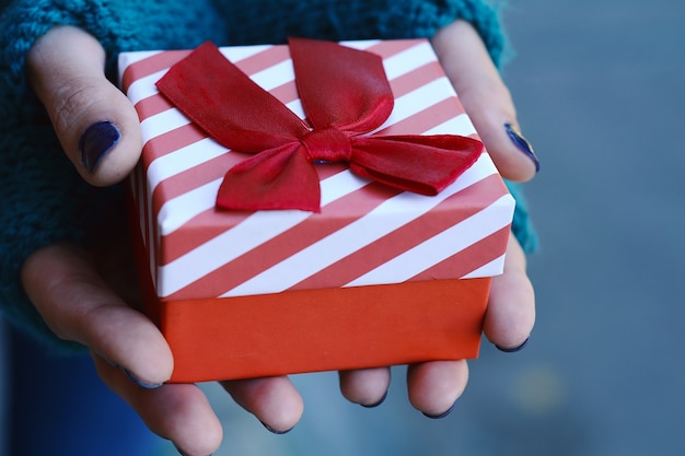 Manos femeninas que sostienen una caja de regalo, presente.