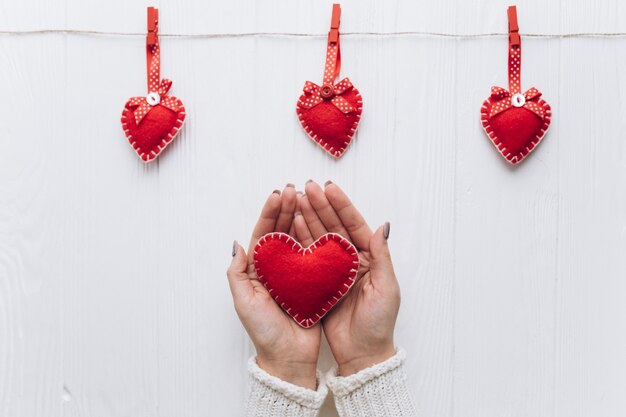 Manos femeninas que sostienen el corazón decorativo para el día de tarjeta del día de San Valentín.