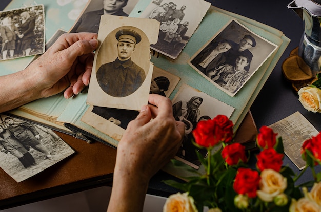 Manos femeninas que sostienen y foto vieja de su abuelo. Álbum de fotos vintage con fotos. Concepto de valores familiares y de vida.