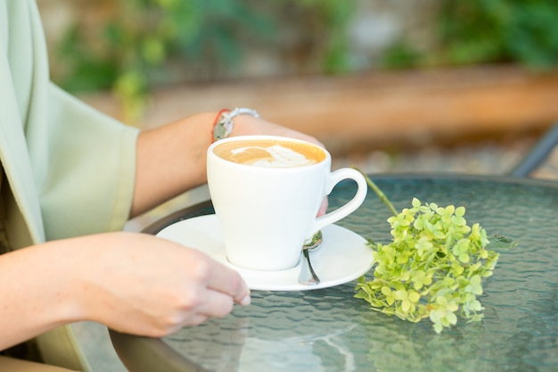 Manos femeninas que sostienen la taza de café en el café