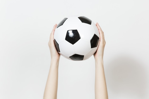 Manos femeninas que sostienen verticalmente la bola negra blanca clásica del fútbol aislada en el fondo blanco. deporte, fútbol, salud, concepto de estilo de vida saludable.