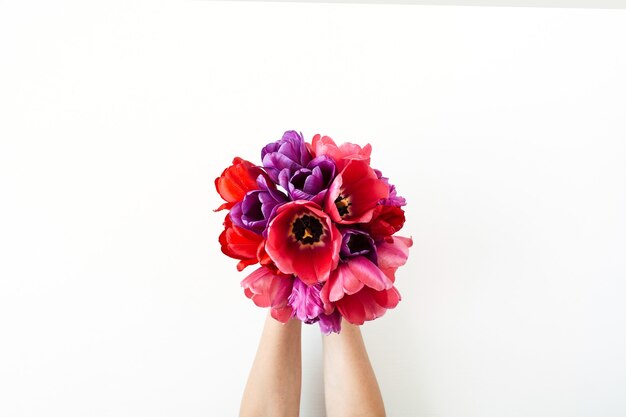 Manos femeninas con ramo de flores de tulipán en blanco